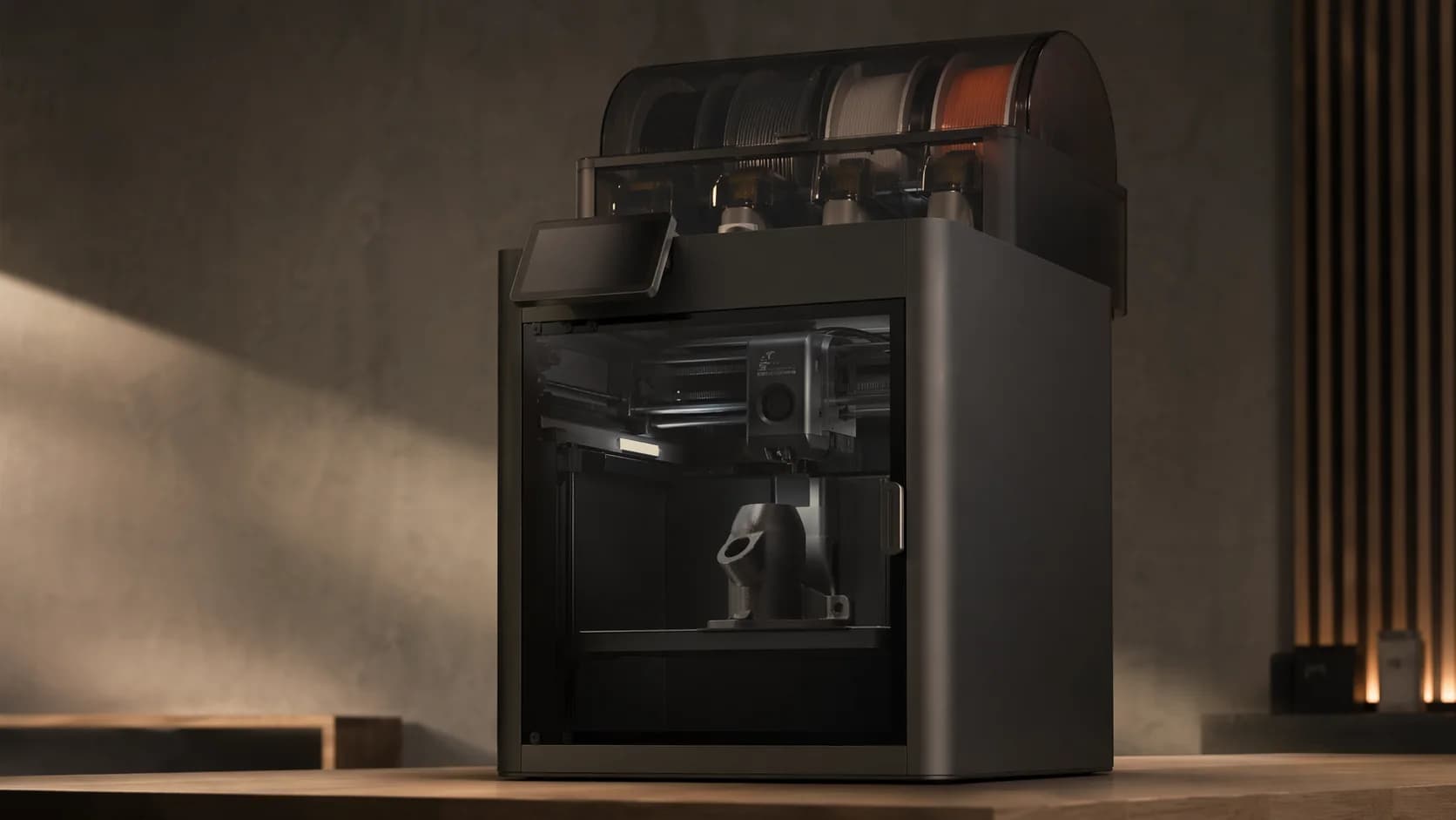 A modern enclosed 3D printer in a quiet studio, with a small functional part on the build plate.